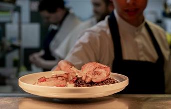 Chef presenting cassoulet through the pass