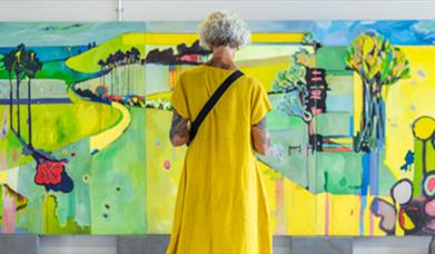 Woman in yellow dress looking at art