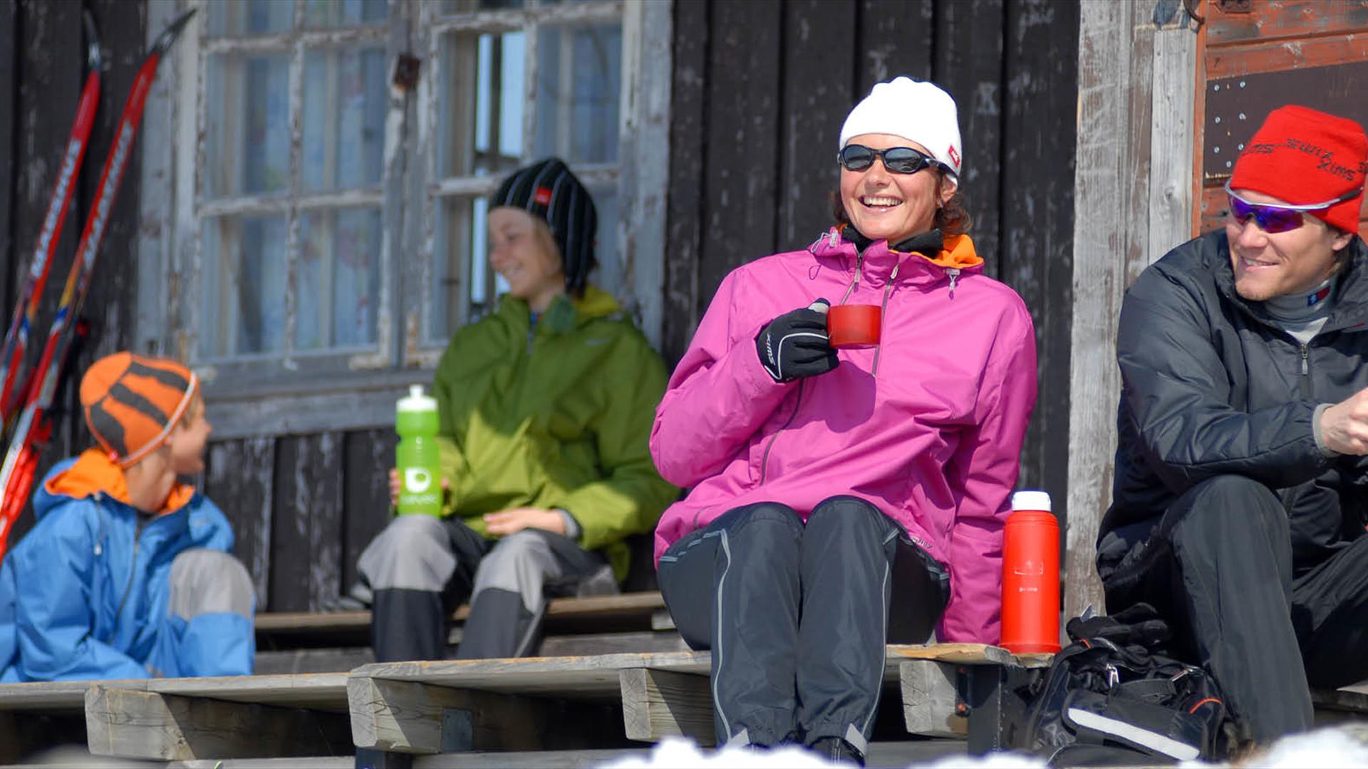 Familie tar en pause i hytteveggen, langrennstur.