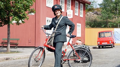 Post woman in historical uniform in front of the Postal Museum at Maihaugen.