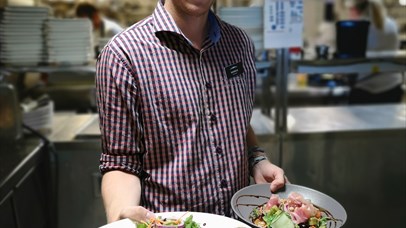 A waiter at Pellestova Kafe is holding two dishes ready to be served