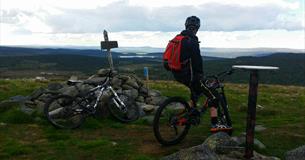 Mountain biker at the top of the mountian Snørvillen at Sjusjøen with a view towards mountains mountains in the distance.