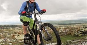 Man on a mountainbike active pedaling up a path in the Skeikampen area.