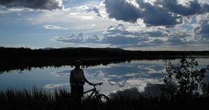 Man standing beside his bike enjoying the view over the Jetningen lake.