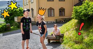 En gutt og en jente som trekker en jente i en gammeldags vogn.