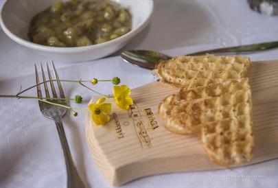 Sour cream waffles on a wooden platter with buttercup flowers. Venabu Fjellhotell