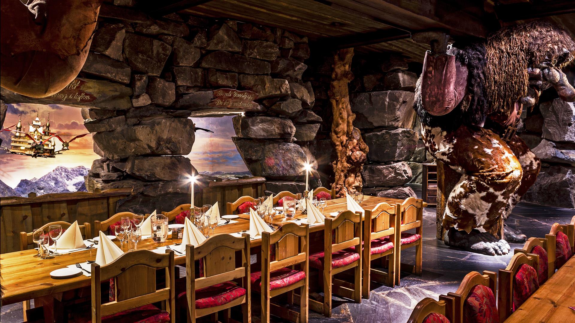 Dekkede bord i Trollsalen i Hunderfossen Eventyrpark der trollene holder taket oppe på skuldrene sine