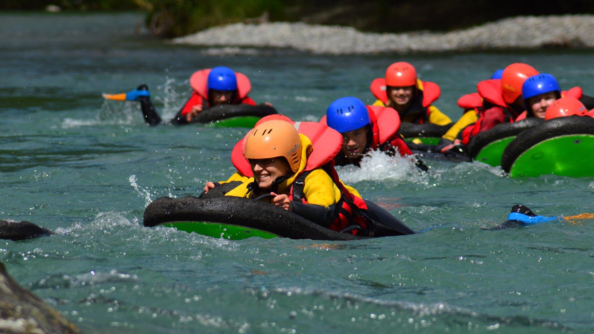 Group wearing helmets and flotation gear in river rapids.