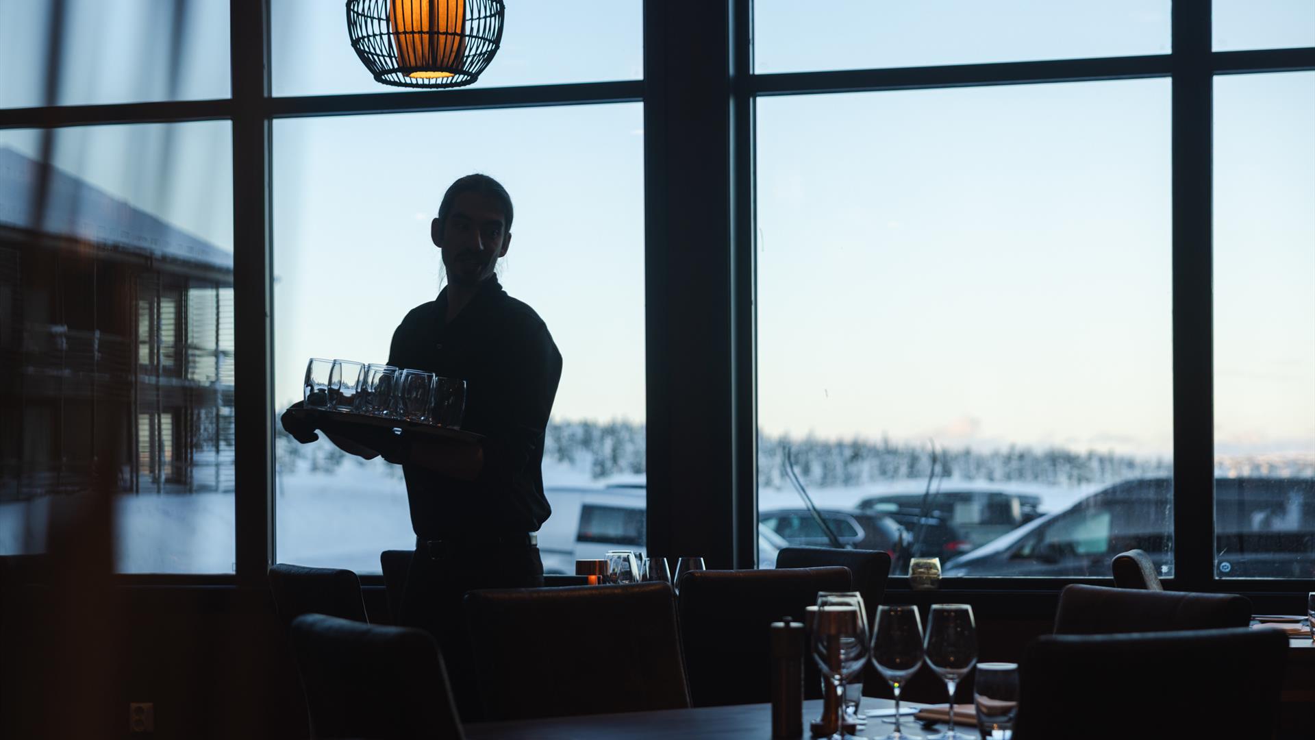 Waitstaff in a restaurant with large window views.