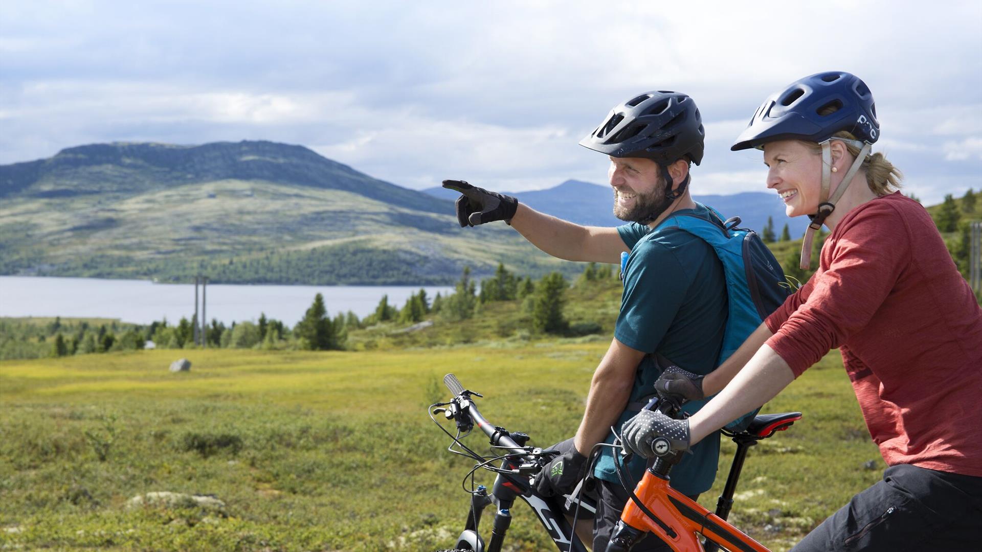 Zwei Mountainbiker genießen den Blick über einen Bergsee.