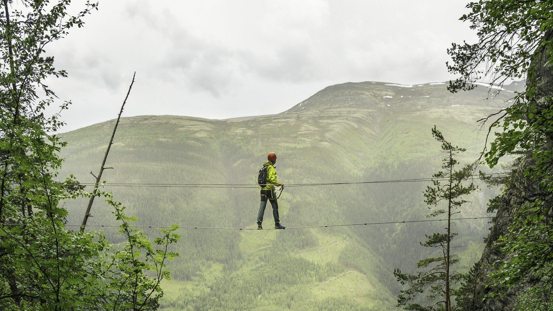Person crossing a high-wire bridge in the mountains.