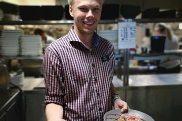 A waiter at Pellestova Kafe is holding two dishes ready to be served