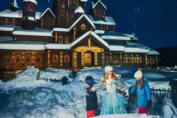Prinsessa i Hunderfossen utenfor eventyrslottet med to barn i vinterparken