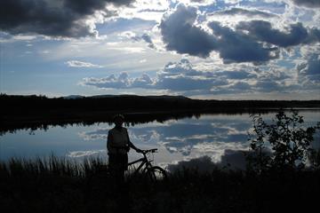 Mann står ved siden av sykkelen og nyter utsikten utover Jetningen vannet.