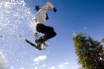 Person jumping with snowshoes and the snow is flying