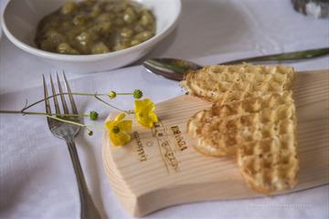 Sour cream waffles on a wooden platter with buttercup flowers. Venabu Fjellhotell