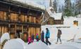 Adults and children entering a historic timber house by Garmo stave church.