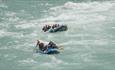 Two rafting boats with groups of participants paddling through rapids.