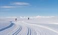 Mountains and cross country skiers on a bluebird day. The peaks of Rondane in view. Spidsbergseter Resort Rondane