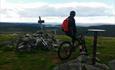 Mountain biker at the top of the mountian Snørvillen at Sjusjøen with a view towards mountains mountains in the distance.