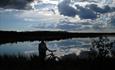 Man standing beside his bike enjoying the view over the Jetningen lake.