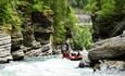 Rafting through a narrow canyon with river and forest.