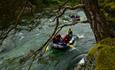 Rafting boat on a river surrounded by trees and rocks.