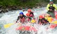 Rafting boat with participants in whitewater rapids.