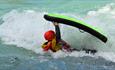 Person kayaking through a wave.
