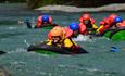 Group wearing helmets and flotation gear in river rapids.