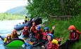 Group gathered by the riverside with rafting equipment
