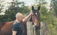Person sammen med hest ved et gjerde.
