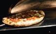 Pizza im Holzofen beim Backen.