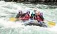 Rafting boat with participants in whitewater rapids.
