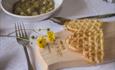 Sour cream waffles on a wooden platter with buttercup flowers. Venabu Fjellhotell