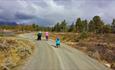 Barnefamilie på tur bortover en grusvei