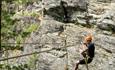 Person traversing a secured rock wall on a via ferrata route.
