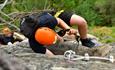 Person wearing a helmet climbing a secured rock face.
