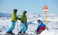 Skiers and a snowboarder getting ready to hit the slopes from the top of Skeikampen Alpinsenter