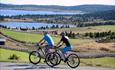 Two bicyclist riding along a mountain road.