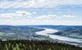 Panoramautsikt over dal, innsjø og skog.