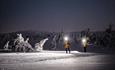 People with headlamps in a nighttime winter landscape