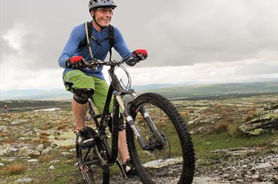 Man on a mountainbike active pedaling up a path in the Skeikampen area.