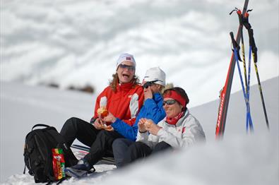 blide damer koser seg med appelsin og sjokolade på skitur