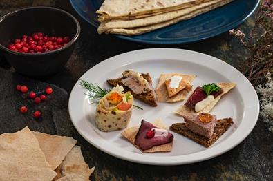 A tasting plate with five pates on toast and a lease roll