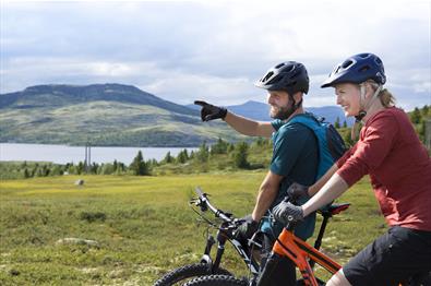 To syklister nyter utsikten utover et fjellvann.