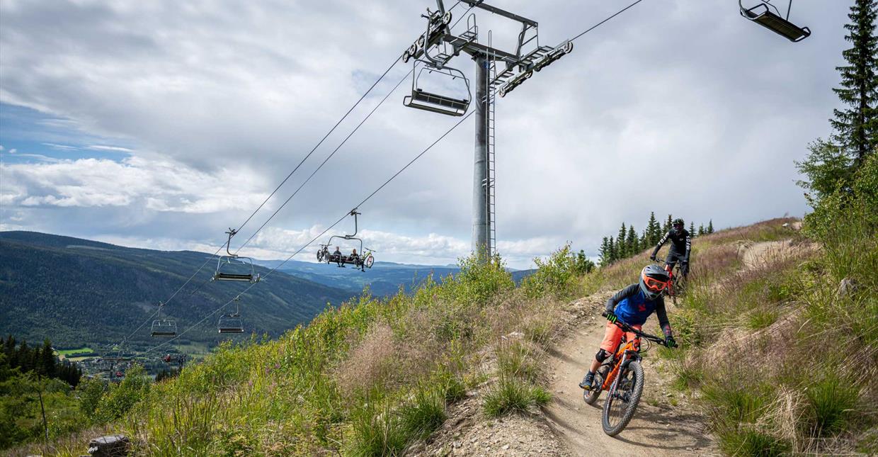 Barn på sykkel ned Hafjell Bike Park, med stolheisen i bakgrunn