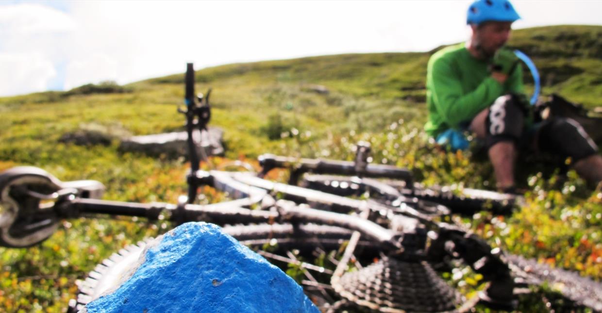 Single Track cyclist sitting by his bike at a mountain ridge at Skeikampen