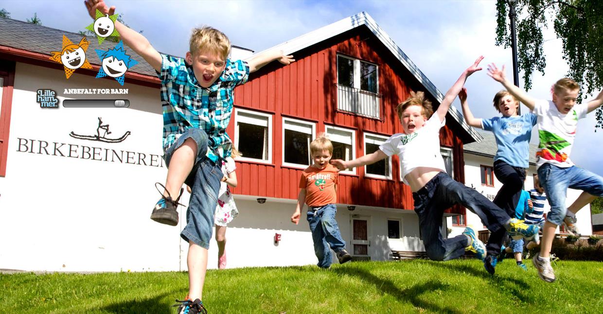 In front of Birkebeineren Hotel & Apartments. Family with children jumping with joy