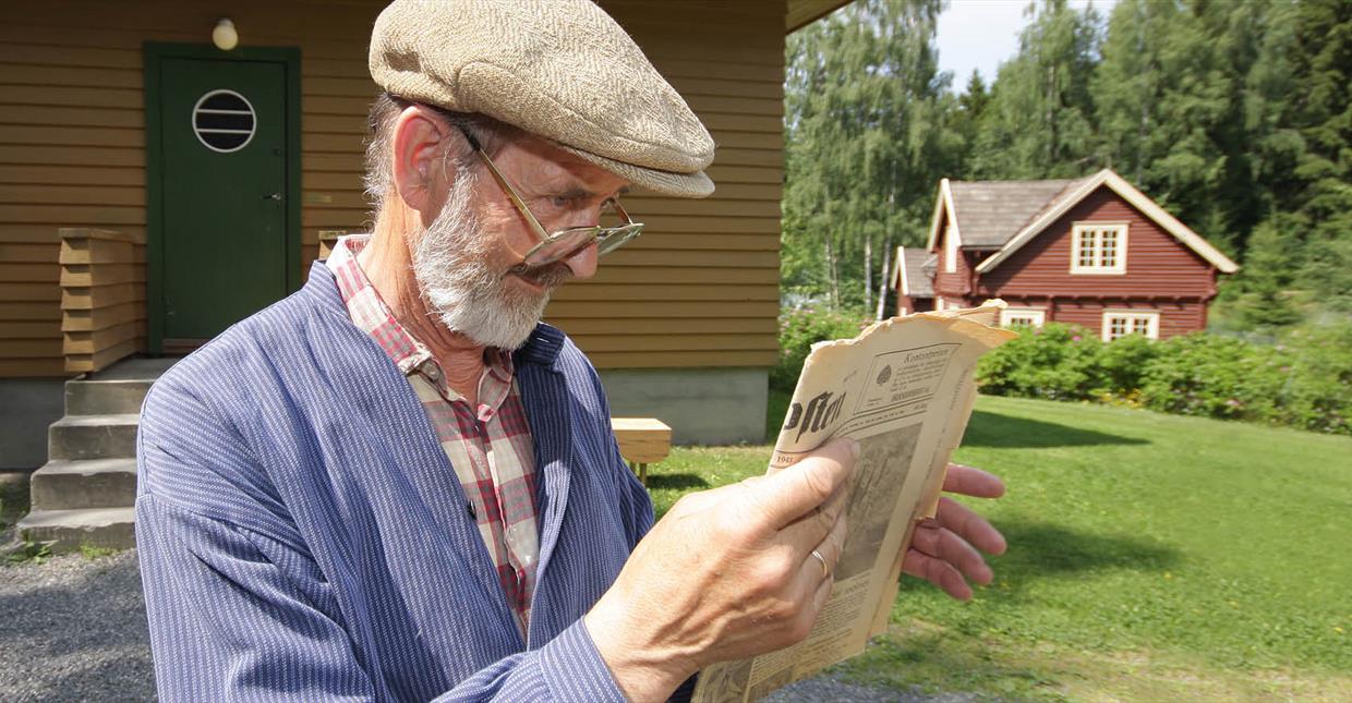 Mann leser avis på Maihaugen